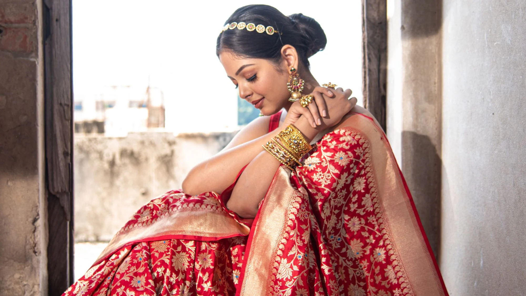 a woman wearing red banarasi saree wth zari barder pallu and jaal motif